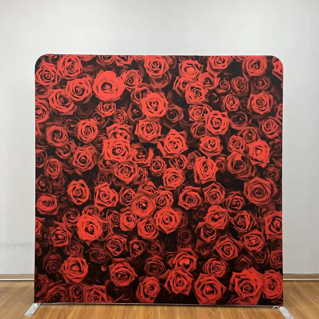 A large event backdrop featuring a dense, wall-to-wall pattern of deep red roses; contact us to book this romantic floral background for your next party.