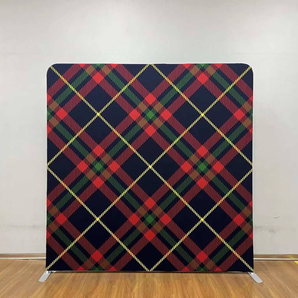 A large event backdrop featuring a classic navy blue, red, and green plaid pattern with yellow intersecting lines; contact us to book this festive holiday background for your next party.