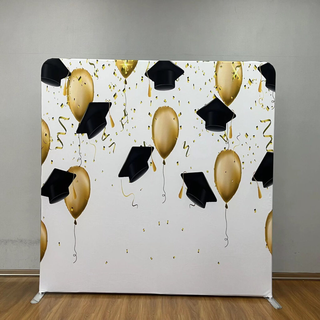 Graduation party backdrop featuring gold balloons and black graduation caps; contact Trill On Wheels to book your graduation celebration.