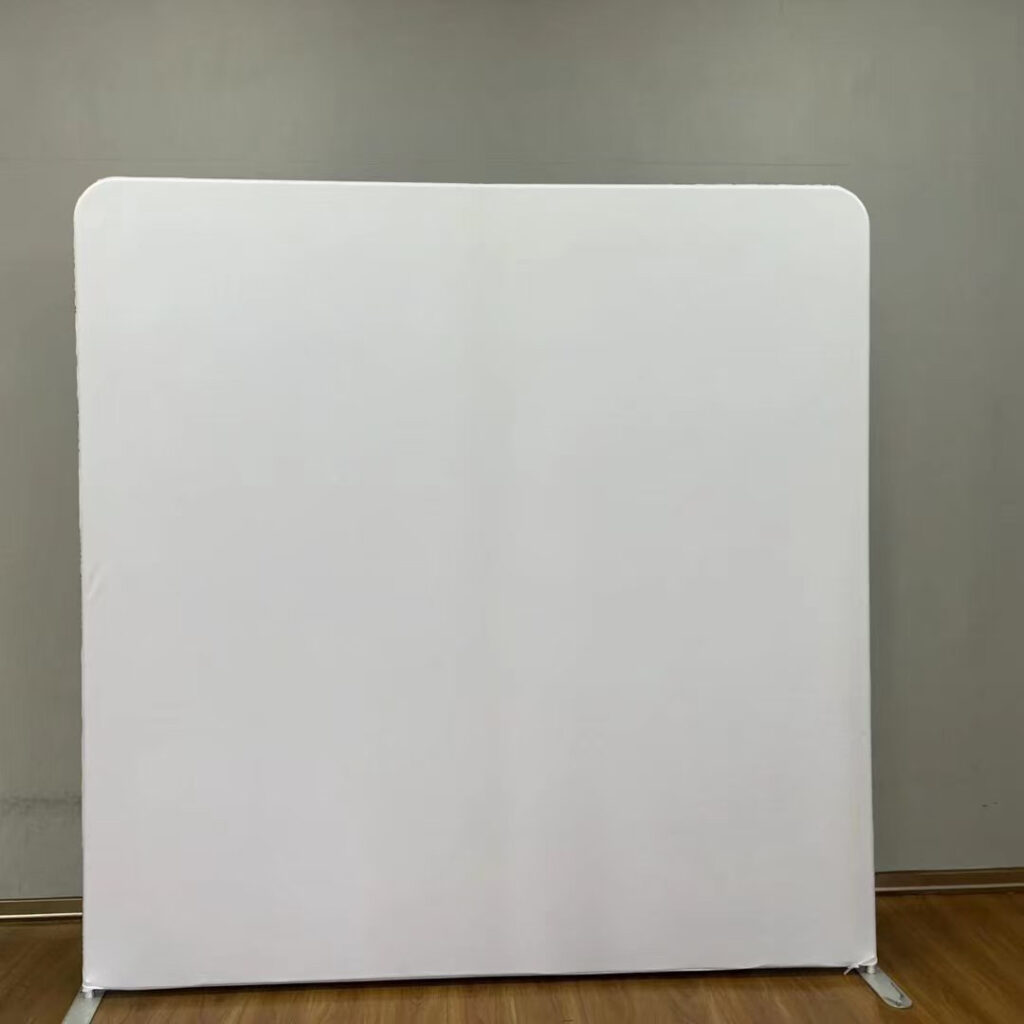 A solid, clean white event backdrop standing on a wooden floor against a grey wall; contact us to book this versatile plain background for your next party.